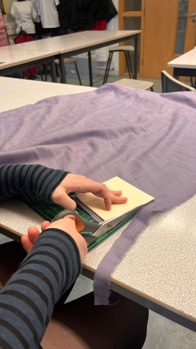 Cutting donated fabric with scissors on a cutting mat