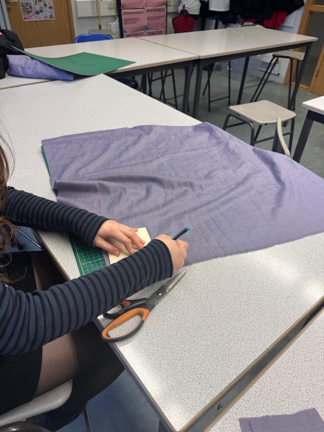 Team member cutting donated fabric with scissors in the workshop